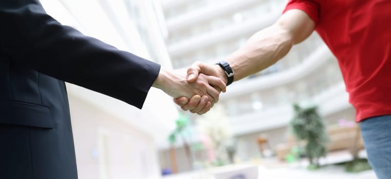 Handshake businessman and men in a red T-shirt, close-up. Freelancer, cooperation agreement. Promotion