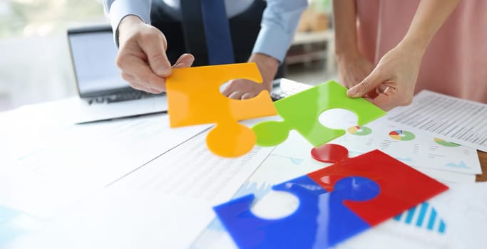 Office workers put together bright jigsaw elements, close-up. Concept teamwork on a project, data analysis, result