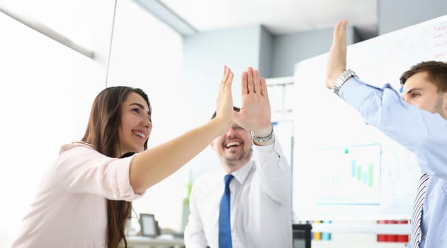Portrait of team clapping hands together giving high five to celebrate finished business project. Successful teamwork in company office. Success concept