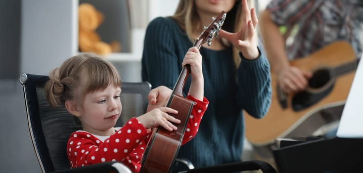 Portrait of mother take musical instrument from daughter hands to show how to play. Parent and daughter form home band. Music, creativity, talent concept