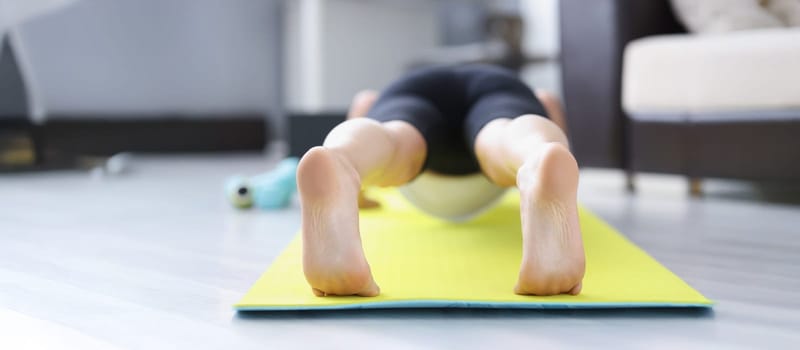 Low angle of male barefoot feet on mat performing exercise in morning for health. Good habit doing sport or yoga after waking up. Lifestyle, hobby concept