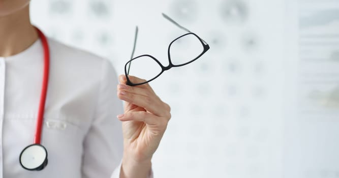 Close-up of professional doctor ophthalmologist hold glasses in black frame. Qualified eye doctor invite on appointment. Vision, medicine, checkup concept