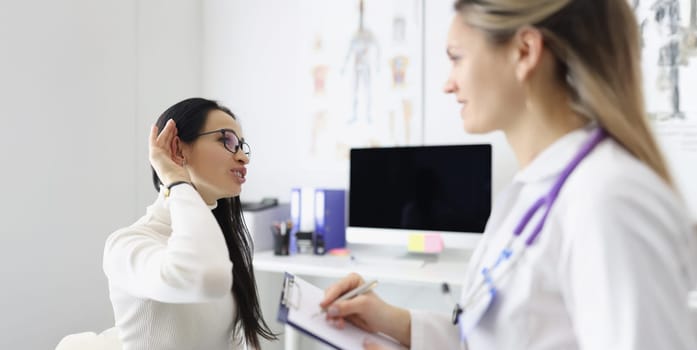 Portrait of client complain on pain in ear and doctor check patients ear on medical examination. Appointment in clinic at otolaryngologist. Health concept