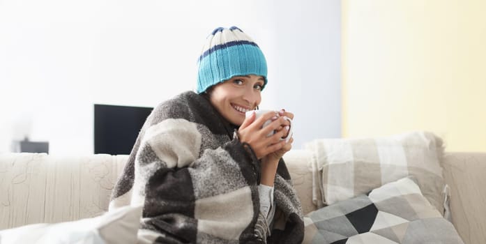 Portrait of sick woman having cup of hot tea drink covered with warm blanket. Unwell girl rest at home on self isolation. Covid, health, quarantine concept