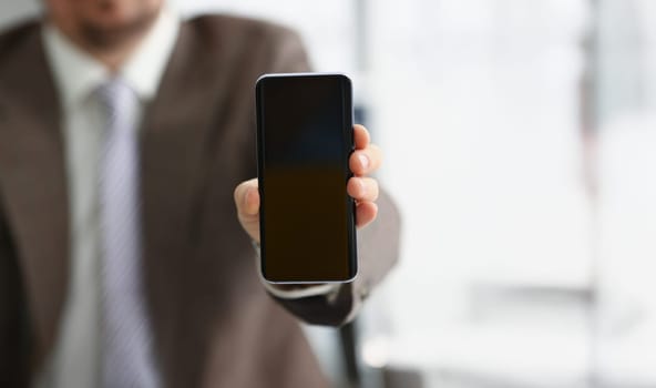 Close-up of male arm in suit show in camera mobile phone display with black screen. Broken or locked smartphone, not working. Mockup, copy space concept
