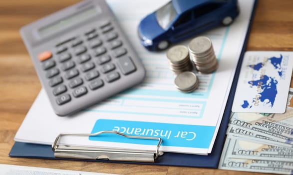 Close-up of car insurance paper calculator stack of coins and banknote on desk. Sign contract and protect your car from accident. Vehicle insurance concept