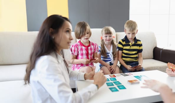 Portrait of group of kids spending time in kindergarten with female teacher. Woman entertain children with games and active pastime. Childhood, fun concept