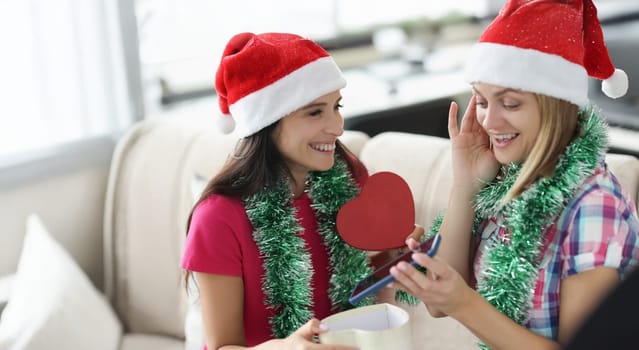 Portrait of woman got present smartphone from sister in heart shaped box. Happy woman shocked and cheerful at same time. New year, christmas, fun concept