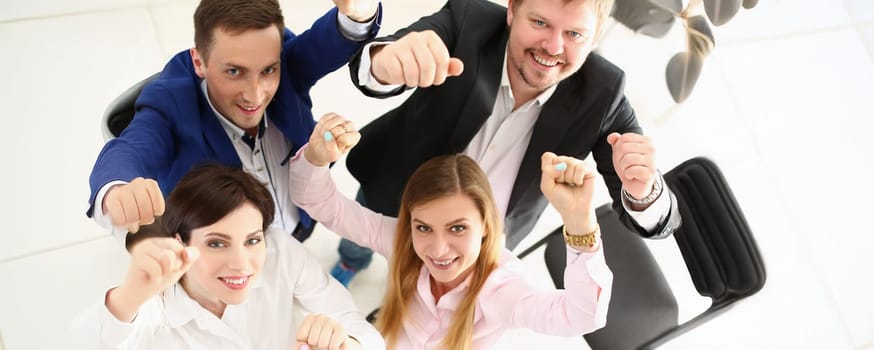 Top view of group of people show support gesture collectively in office. Well dressed workers posing with smile, cheerful mood. Business, teamwork concept
