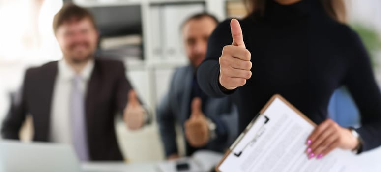 Close-up of group of young businesspeople happy to make good deal show thumbs up. Business partners made successful agreement in office. Business concept