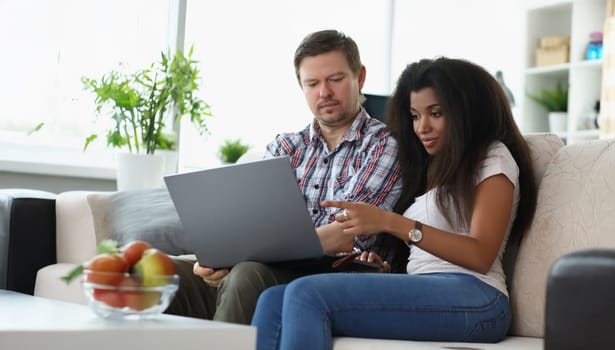 Portrait of middle aged man and latino american woman choosing something online. Couple want to buy furniture via online store. Online shopping concept