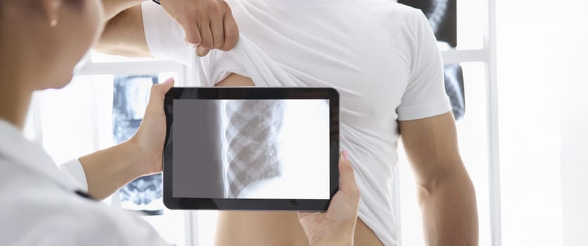 Close-up of medical worker put tablet device on patients body part and see ribs. Fast development of medicine. Modern technology, medicine, checkup concept