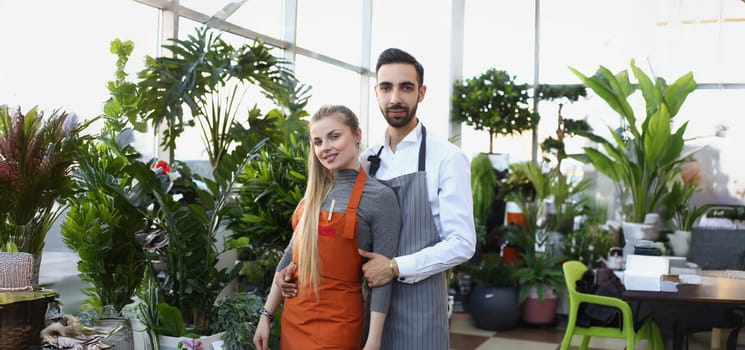 Portrait of pretty young consultants work in small flower delivery shop and sale indoor plants in pots. Business, floral design, creative studio concept