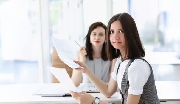 Portrait of business women working on monthly report surrounded with bunch of papers. Colleagues workers in company office. Business, corporate concept