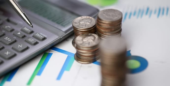 Close-up of silver calculator with keyboard lying on desk cash quarter plots in home office setting. Calculation of family expenses, social income concept