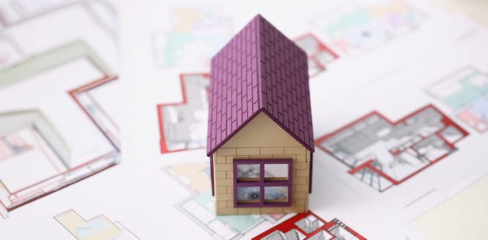 Close-up of house miniature with blueprint sample for real estate property development. Small model of future building. Real estate, architecture concept