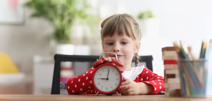Portrait of cute child learn how to understand time and play with red retro clock. Curious look and interest in little childs eyes. Development concept