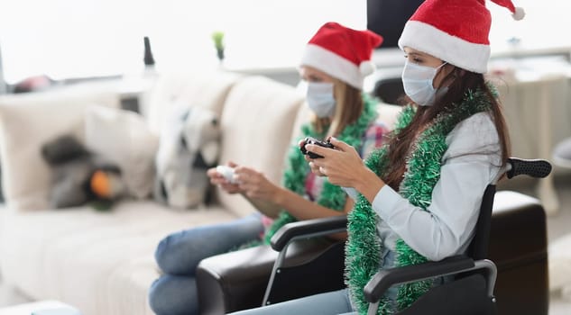 Portrait of young women playing video game for fun using controlling joystick. Happy pastime in room with visitor, celebrate new year. Disabled concept