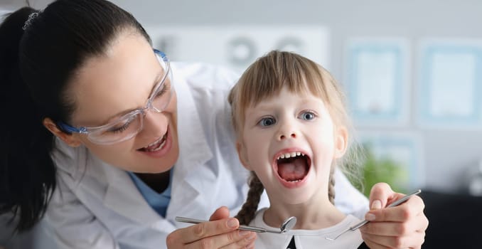 Portrait of cute kid visiting family doctor and open mouth pediatrician with tool check hurting throat. Healthcare, medicine, clinic, childhood concept
