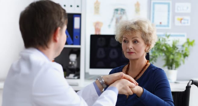 Portrait of professional doctor hold patients hand and calm down after appointment. Senior woman in doctors cabinet, checkup health. Medicine, help concept