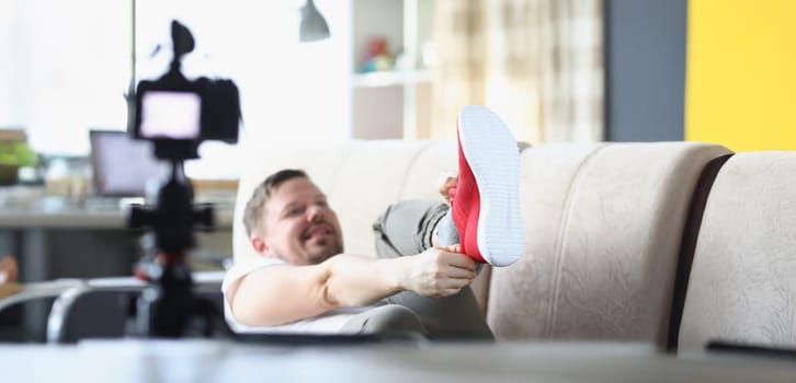 Close-up of middle aged male putting on trendy red sneaker showing on camera. Try on new model of comfy shoe for jogging. Social media, fashion concept