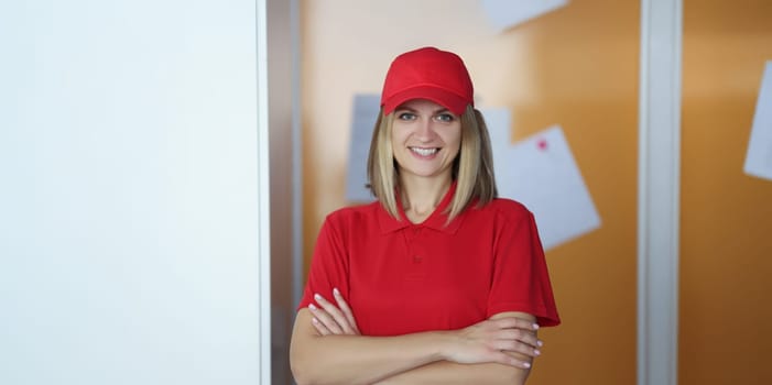 Portrait of happy blonde lady courier in red shirt and cap uniform. Positive mood, best worker of year. Delivery service, shipping, private courier concept
