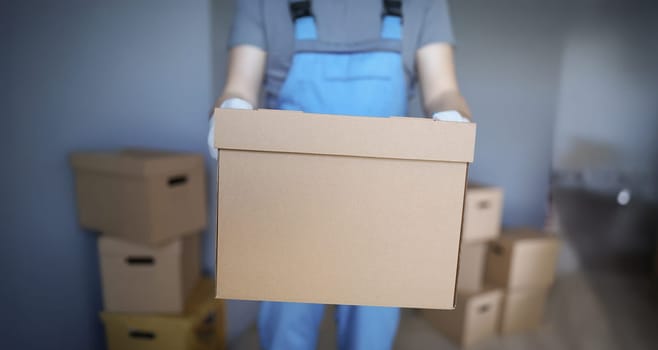 Close-up of worker loading cardboard boxes with owners belongings to new apartment. Guy from delivery service help with relocation. Loader, moving concept