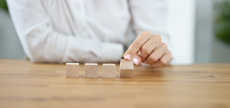 Close-up of business woman flipping one wooden cube from row. Change situation, positive thinking. Success, strategy, solution, progress, business concept