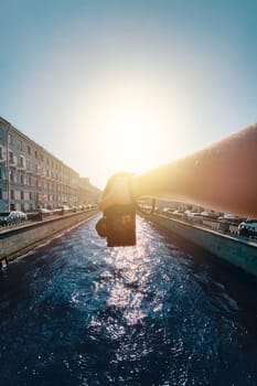Holding a camera by the riverside amidst historic architecture, a male hand captures a photo from a first-person perspective. pov