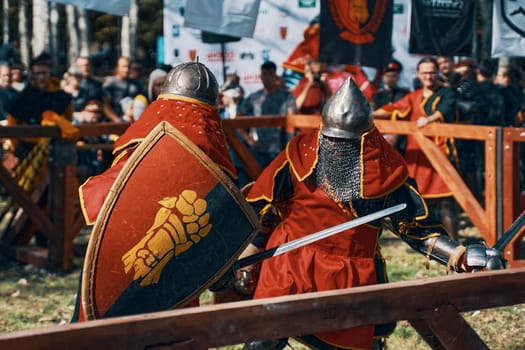 Two knights fight with swords. On the knight's shield is an image of a Golden glove. Simulation of medieval battles during the festival of historical clubs. Bishkek, Kyrgyzstan-October 13, 2019.