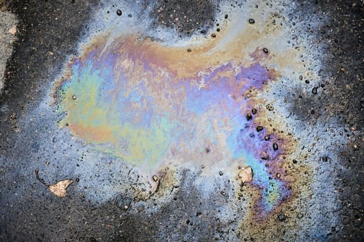 A car leaking oil or gasoline onto a wet asphalt road on a wet fall day.