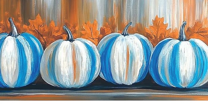 A row of uniquely painted pumpkins showcases shades of white and blue, surrounded by vibrant autumn leaves, creating a warm seasonal atmosphere.