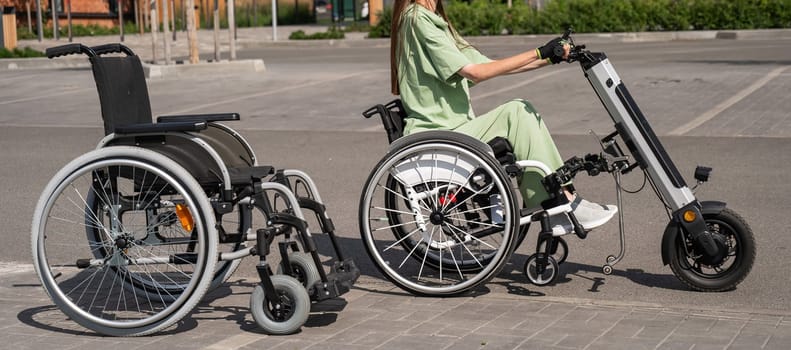 Woman in wheelchair with assistive device for manual control next to classic wheelchair. Electric handbike