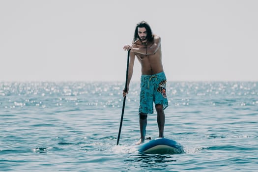 Man Sea Sup. Strong athletic man learns to paddle sup standing on board in open sea ocean on sunny day. Summer holiday vacation and travel concept. Aerial view. Slow motion.
