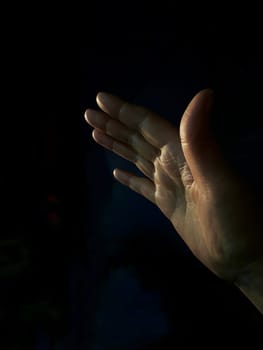 A woman's hand stretched up and forward to the light, the concept of asking for help, salvation, faith. High quality photo