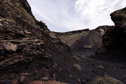 scenery view of volcano Cuervo and rough mountains under cloudy sky in Tinajo, Lanzarote at Canary Islands, Spain, concept of volcanic landscape