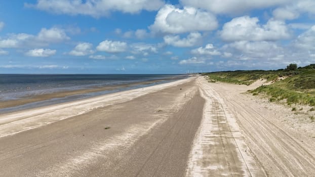 a photo taken of the North Sea beach at Rockanje in the Netherlands in the summer with the windmills in the background