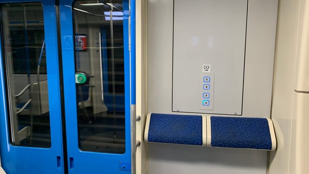 Interior of subway train near sliding doors, special standing places with ledge to lean next to USB charging ports for convenience in modern urban transport during rush hour in metro