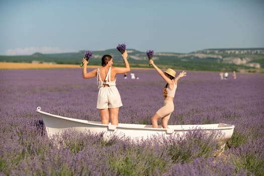 women and girl standing in a field of lavender, holding flowers and smiling. They are in a small boat, which is floating on lavender.