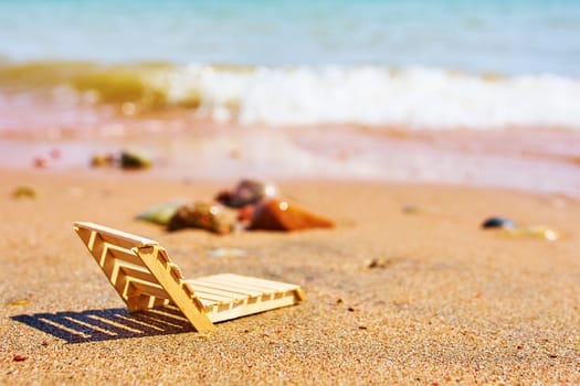 Wooden deckchair on a tropical sand beach. Wooden deckchair on a tropical sand beach overlooking the sea water.