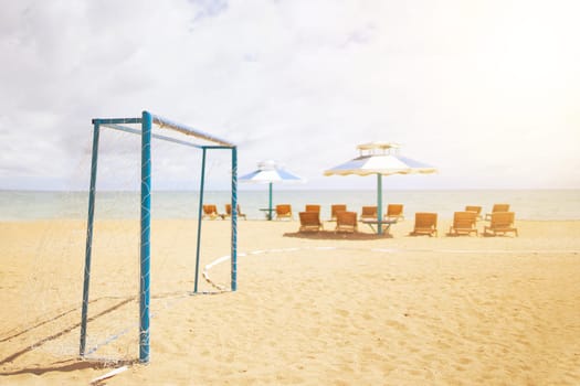 Football goal on the beach on the background of the sea and thighs with umbrellas