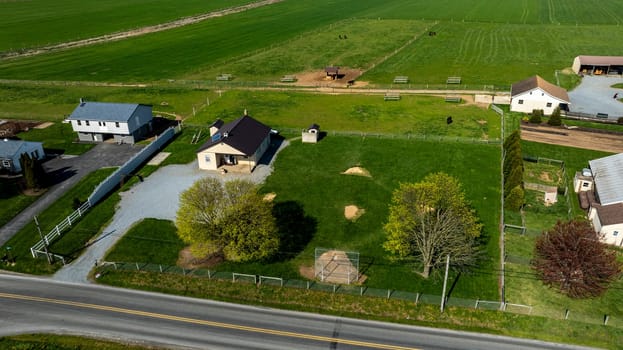 A vast expanse of open farmland an Amish one room school house surrounded by lush green pastures and a clear blue sky. The property showcases a serene rural setting, ideal for country living.