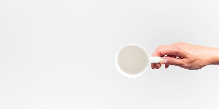An empty white ceramic cup in a female hand on a white background, banner food mockup, top view