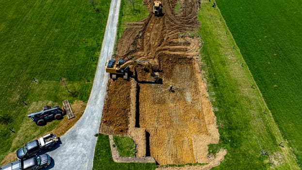 An excavator is digging into the ground to prepare a foundation for building a new structure in a residential neighborhood. The area is clear, showcasing the construction site layout.
