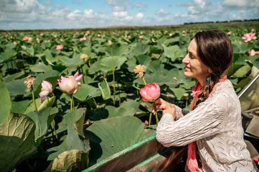 A woman is sitting in a boat in a field of pink lotus flowers