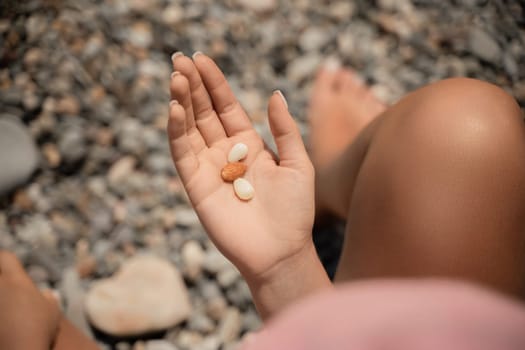 A person is holding a handful of nuts in their hand. The nuts are of different sizes and shapes, and they appear to be almonds. The person seems to be enjoying the nuts and is likely to eat them soon