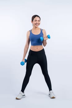 Vigorous energetic woman doing dumbbell weight lifting exercise on isolated background. Young athletic asian woman strength and endurance training session as body workout routine.