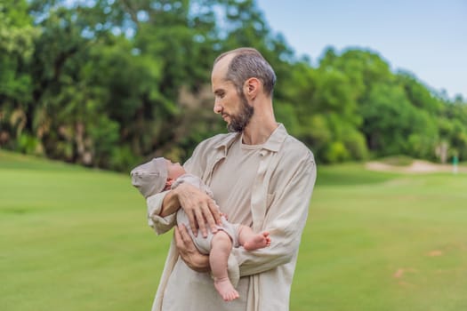 A happy 40-year-old father cradles her newborn in a sun-drenched park. Love, family and generations in harmony.