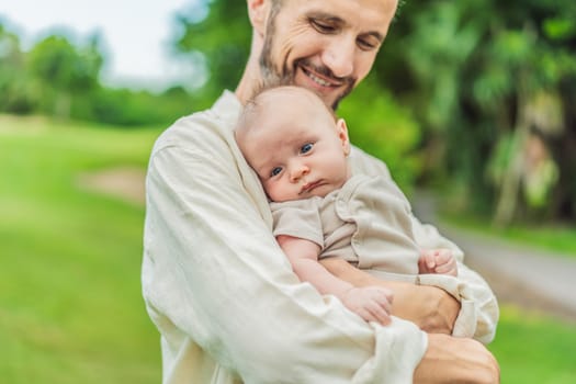 A happy 40-year-old father cradles her newborn in a sun-drenched park. Love, family and generations in harmony.