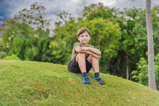 Young boy sitting in the grass on a sunny day.